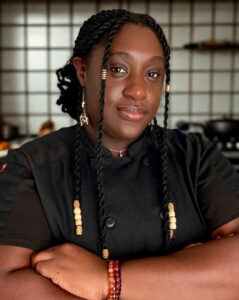 Chef Meka Haynes, Holistic Culinary Creative, standing in a chef coat, preparing the Food That Refuels Her brunch.